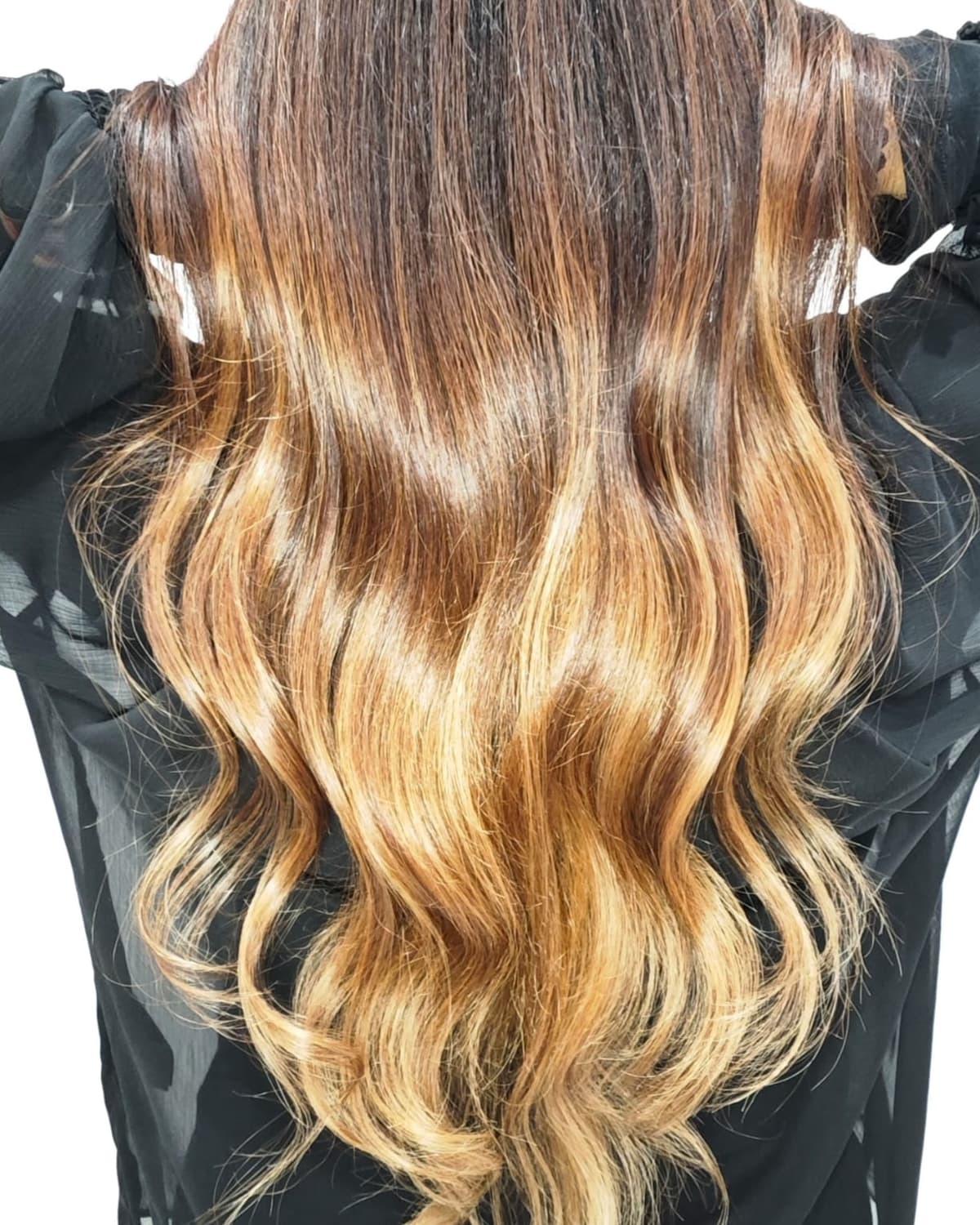 Rückansicht von dunklem Ansatz zu goldblonden Längen mit Wellen, gefärbt im Oxygeni Hair Salon Wien